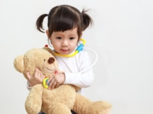 little asian girl or a little cute asian girl doctor examining teddy bear