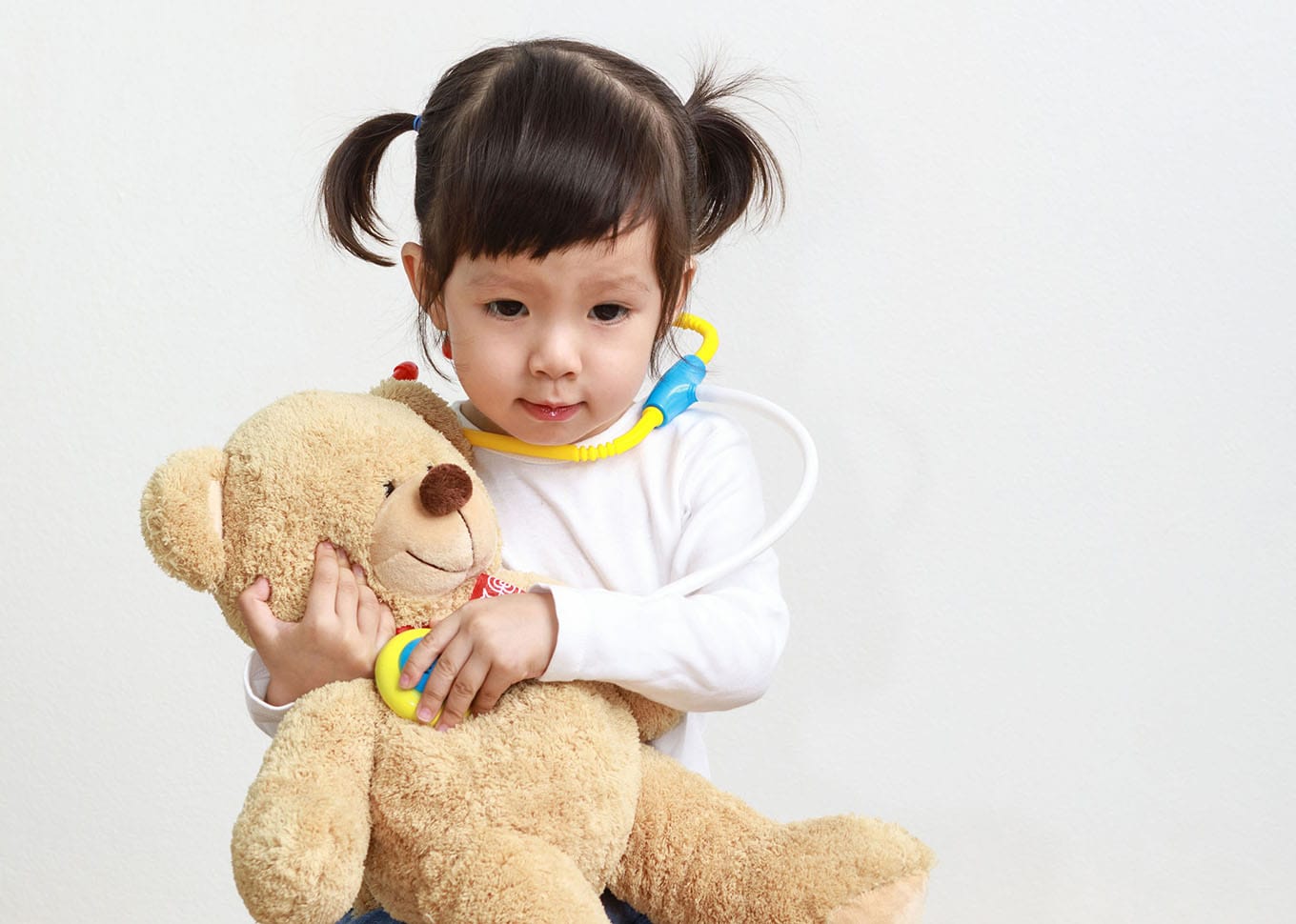 little asian girl or a little cute asian girl doctor examining teddy bear